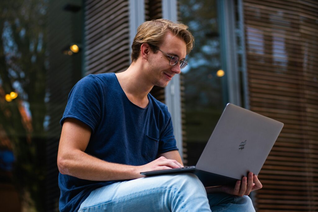  A young digital marketing freelancer working on a laptop outdoors, focused on creating online strategies and managing campaigns.